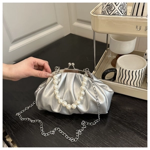 Detail of silver pleated cloud bag featuring large pearl handle and metallic chain strap