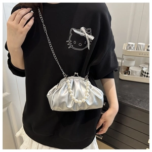 Detail of silver pleated cloud bag featuring pearl handle and retro metal clasp closure