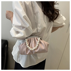 Detail of crossbody bag with white pearl handle and pleated texture design