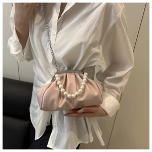 Detail of pink pleated cloud bag featuring pearl handle and silver metal chain strap