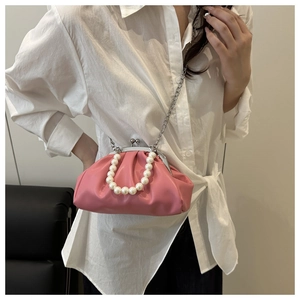 Detail of pink pleated clutch bag featuring a pearl handle and silver metal clasp