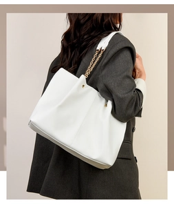 Vista posteriore della modella con borsa tote in PU bianca con catena d'oro e rivetti
