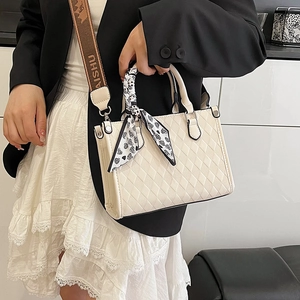 Beige quilted tote bag with lettered strap and heart-print scarf, shown on a model