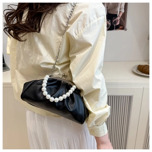 Close-up of pearl handle and pleated black faux leather cloud bag with metal clasp