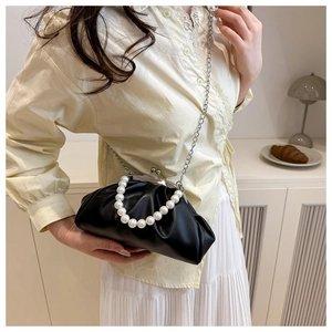 Detail of black pleated cloud bag featuring pearl handle and vintage metal clasp