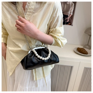 Detail of black pleated cloud bag with large pearl handle and silver metal chain strap