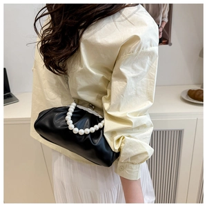 Detail of black pleated cloud bag with elegant pearl handle and vintage metal clasp
