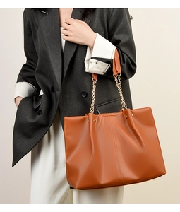 Dettaglio della borsa tote in morbida pelle PU marrone con catena dorata e texture a pieghe