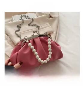 Detail of pink pleated clutch bag featuring large pearl handle and silver chain strap
