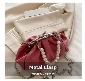 Detail of pink pleated cloud bag featuring gold hardware kiss-lock and pearl handle