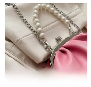 Detail of pink pleated cloud bag featuring silver clasp and elegant pearl chain strap