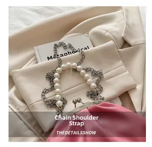 Detail of pink ruched clutch bag with pearl chain strap and silver metal clasp