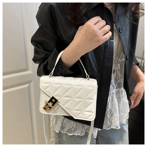Close-up of white quilted crossbody bag with gold lock and elegant chain strap detail