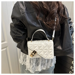 Close-up of white quilted crossbody bag with asymmetric flap and black-gold lock
