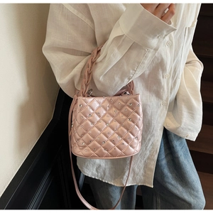 Detail of pink quilted bucket bag with rhinestones and woven handle on casual outfit