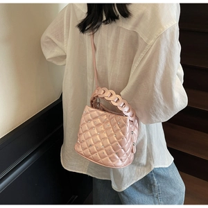 Macro detail of pink quilted bucket bag featuring rhinestone accents and woven chain handle