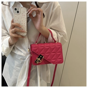 Detail of rose pink crossbody bag with triangular quilting and gold hardware lock