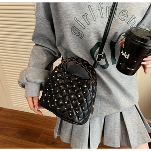 Detail of black quilted bucket bag with rhinestones and woven handle on a casual model