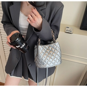 Detail of silver quilted bucket bag with rhinestones and metal chain handle on model