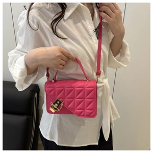 Detail of rose red quilted crossbody bag with gold chain and elegant lock closure