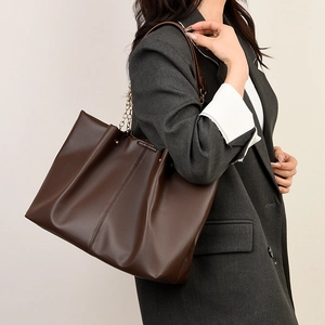 Borsa tote marrone a pieghe con catena dorata indossata da modella per il lavoro
