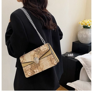 Détail du sac à bandoulière motif serpent avec boucle tête de tigre et chaîne