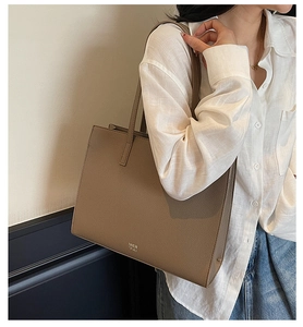 Dettaglio di una borsa tote marrone in pelle martellata con logo MER PAI e tracolla