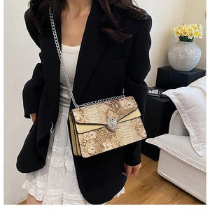 Détail du sac texture peau de serpent avec boucle tête d'animal et chaîne en argent