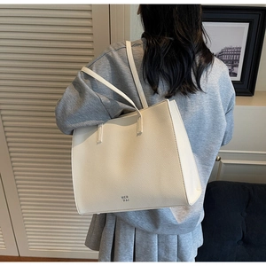 Dettaglio della borsa tote beige in pelle martellata con logo MER PAI e tracolle