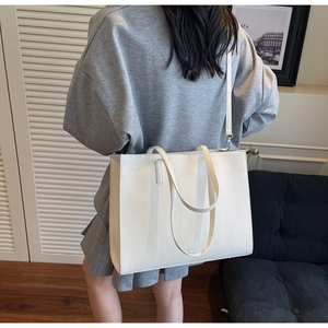 Dettaglio della borsa tote bianca in pelle martellata indossata da una modella in casa