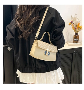 Close-up of cream crossbody bag with signature brand print and golden oval clasp detail