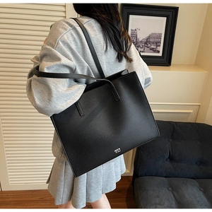 Dettaglio della borsa tote in pelle nera a grana litchi con il logo bianco MER 'PAI