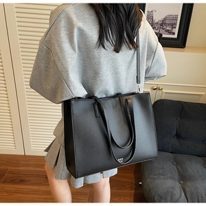 Dettaglio della borsa tote in pelle nera martellata con elegante logo bianco