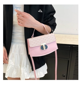 Detailed shot of pink crossbody bag with a gold T-shaped lock and long shoulder strap