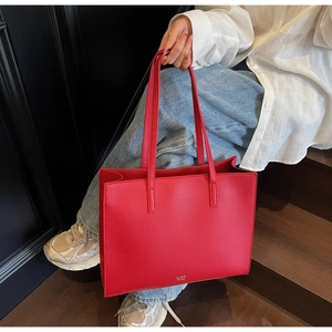 Dettaglio della borsa tote in pelle rossa a grana di litchi con logo in metallo