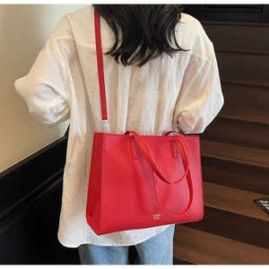 Dettaglio della borsa tote rossa in pelle granata con logo MER PAI portata da modella