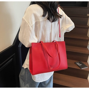 Dettaglio borsa tote rossa in pelle martellata con tracolla e piccolo logo dorato