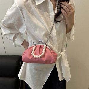 Pink dumpling bag with pearl handle and silver chain strap shown on white shirt outfit