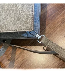 Dettaglio dei ganci metallici argentati sulla borsa tote in pelle grigia
