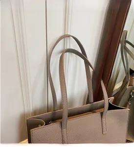 Dettaglio della pelle con grana litchi e manici rinforzati su una borsa tote capiente