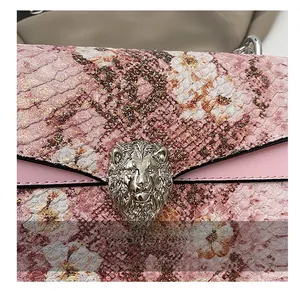Détail du cuir rose gaufré serpent avec imprimé floral et boucle lion en métal
