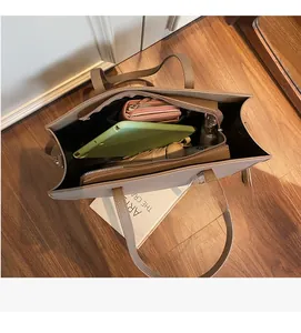 Vista dall'alto dell'interno capiente della borsa tote in pelle marrone con oggetti quotidiani