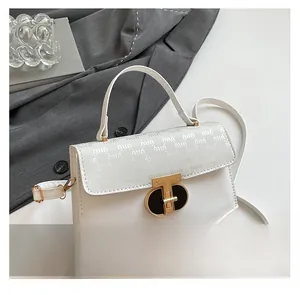 Detail of white leather crossbody bag with geometric texture and gold oval twist lock