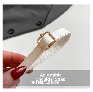 Detail of adjustable white leather shoulder strap with polished gold buckle and stitching
