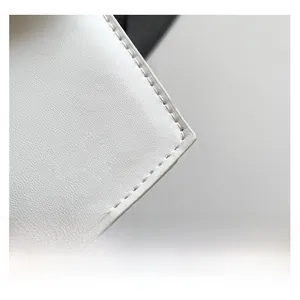 Close-up of white pebble leather texture and fine stitching detail on a square handbag