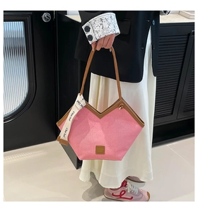 Detail of pink canvas tote bag with brown leather trim and decorative ribbon