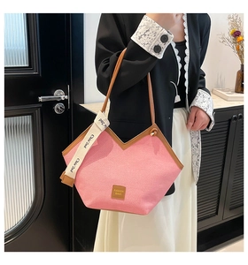 Detail of pink canvas tote bag with brown leather trim and printed decorative ribbon