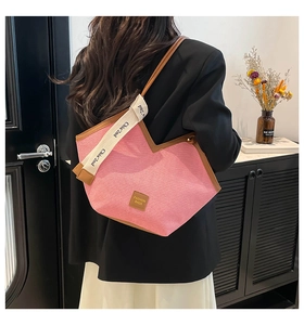 Detail of pink canvas tote bag featuring brown leather trim and chic shoulder strap