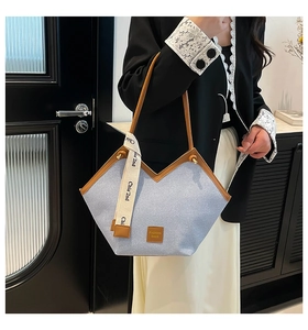 Close-up of blue denim tote bag featuring a V-shaped opening and brown leather trim details