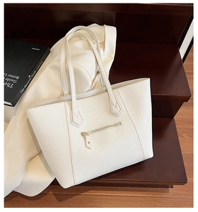 Close-up of white pebble leather tote bag with gold zipper on a wooden stair